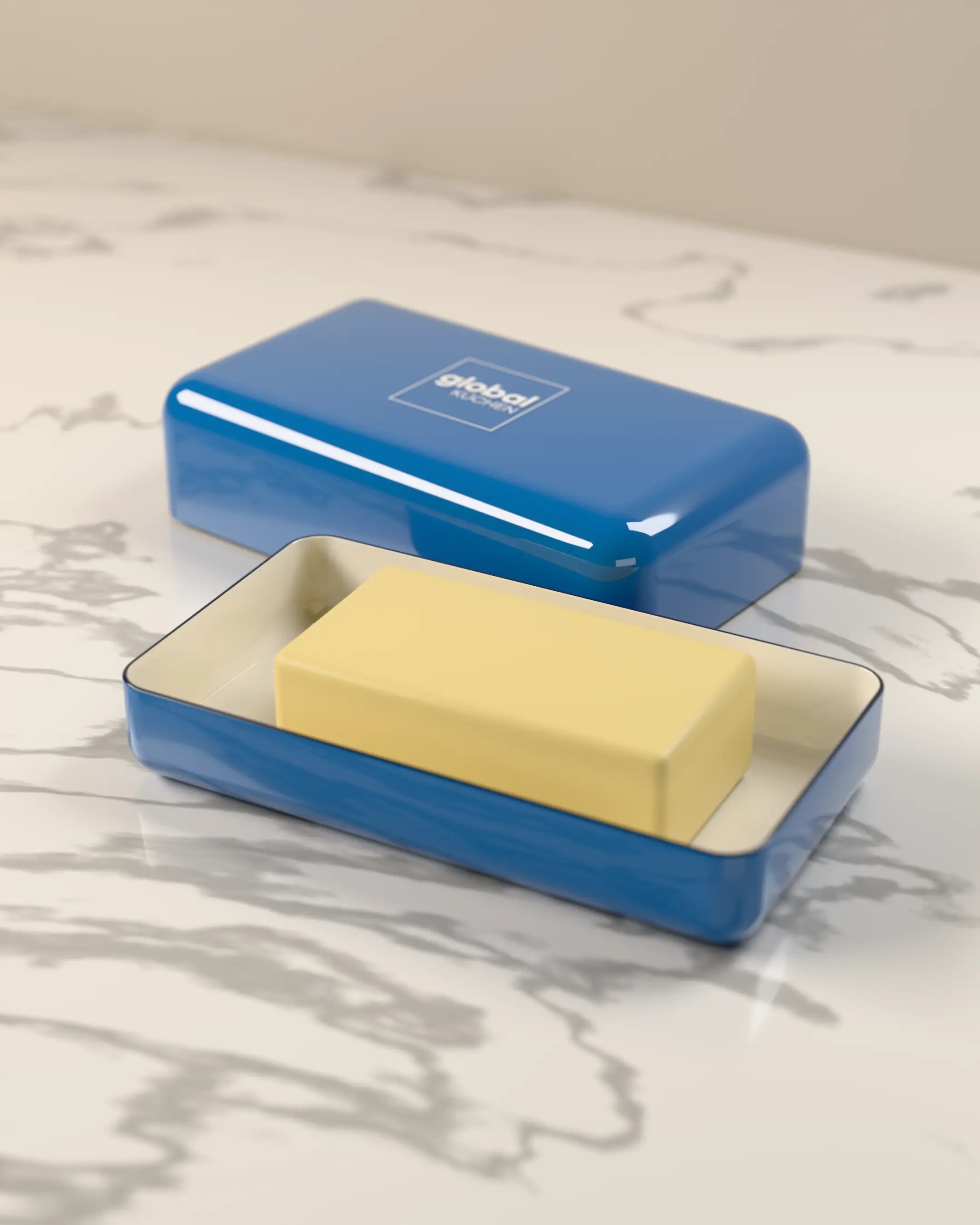Blue enamel butter dish on marble, lid set aside with the Global Küchen logo, a block of butter in the tray